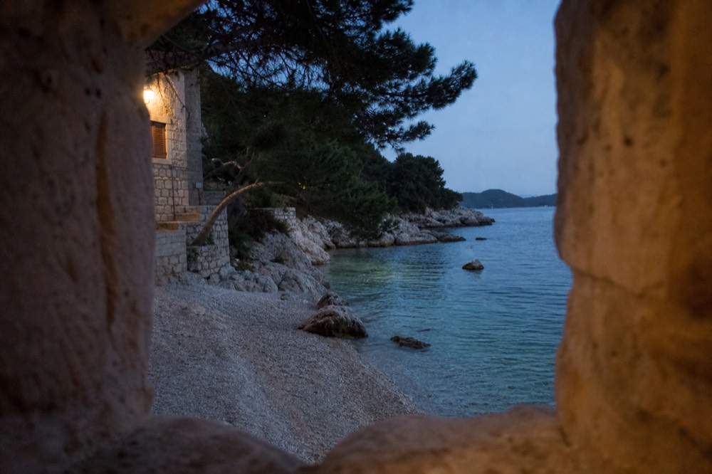 Pebble beach with clear shallow water and pine trees at a Dalmatian bay
