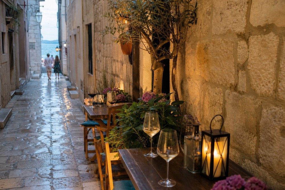 Evening café tables on a stone street with wine glasses and lantern light