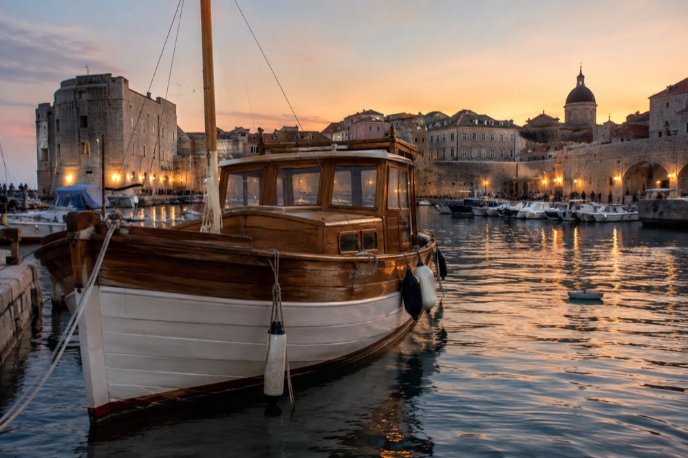 A wooden boat moored in the old city harbour at golden hour