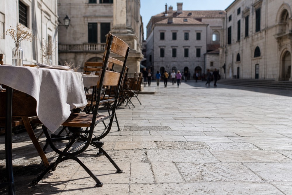 Outdoor restaurant tables on a quiet Dubrovnik square in autumn