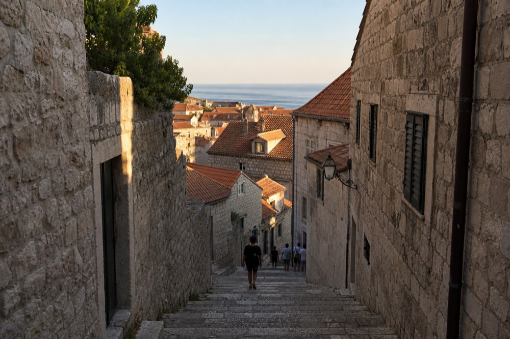 Shaded stone staircase street in Dubrovnik Old Town lined with worn stone steps