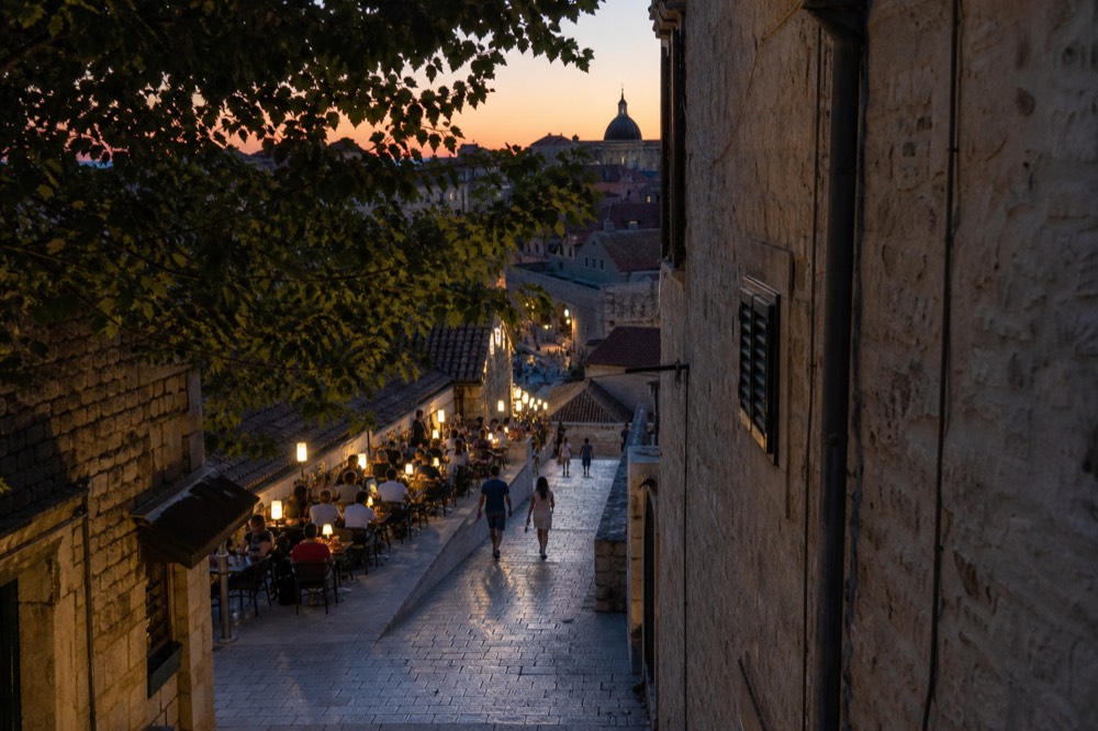 Evening terrace restaurant lights along a Dubrovnik street at dusk