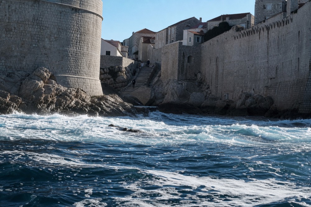 Dark winter sea washing against the rocks below the city walls with white foam on the swell