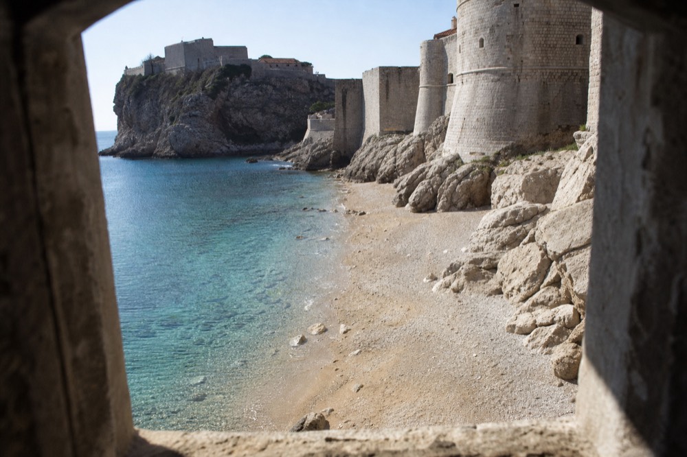 Empty stone beach below the city walls with clear winter water and no people