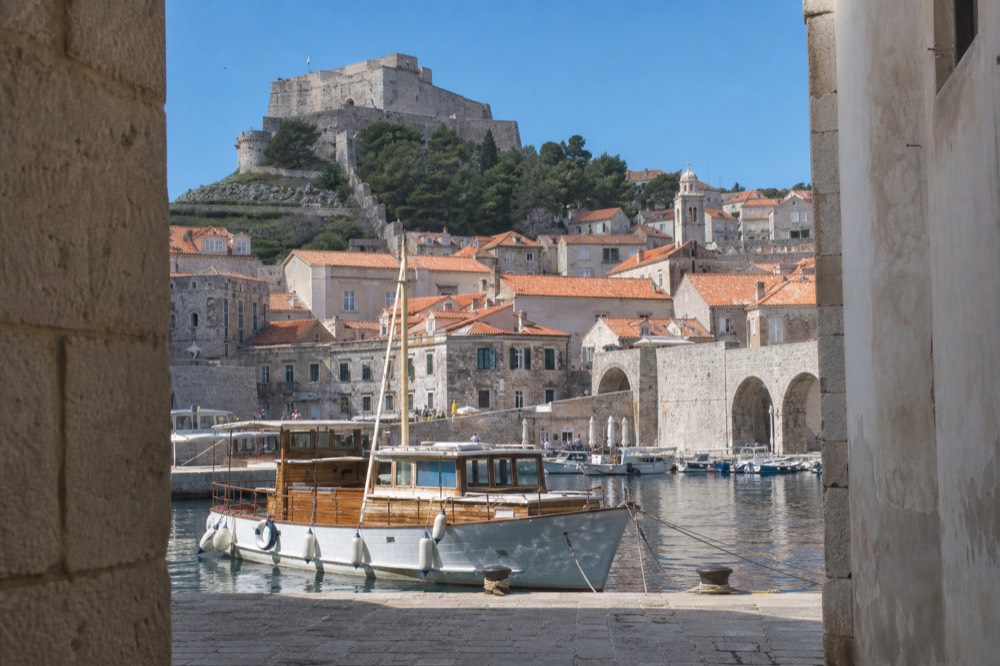 A wooden boat moored in the Old City Harbour on a still winter morning with the fortress above
