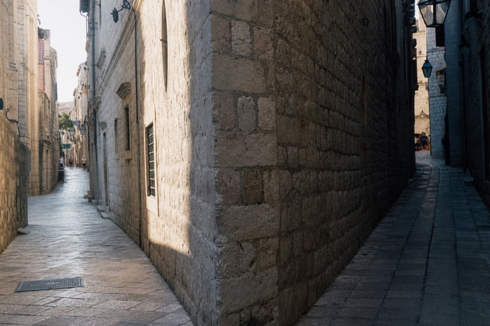 A shaded corner where two narrow limestone lanes meet in Dubrovnik's Old Town