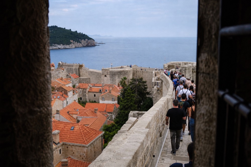 Crowds walking the City Walls at midday with the Old Town rooftops below
