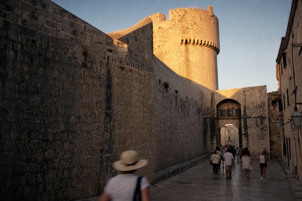 Medieval stone gate and fortified wall tower above a busy Old Town street