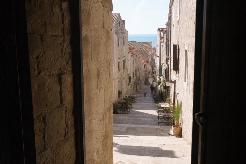 Grand stone staircase inside the Old Town lined with pale buildings and café tables