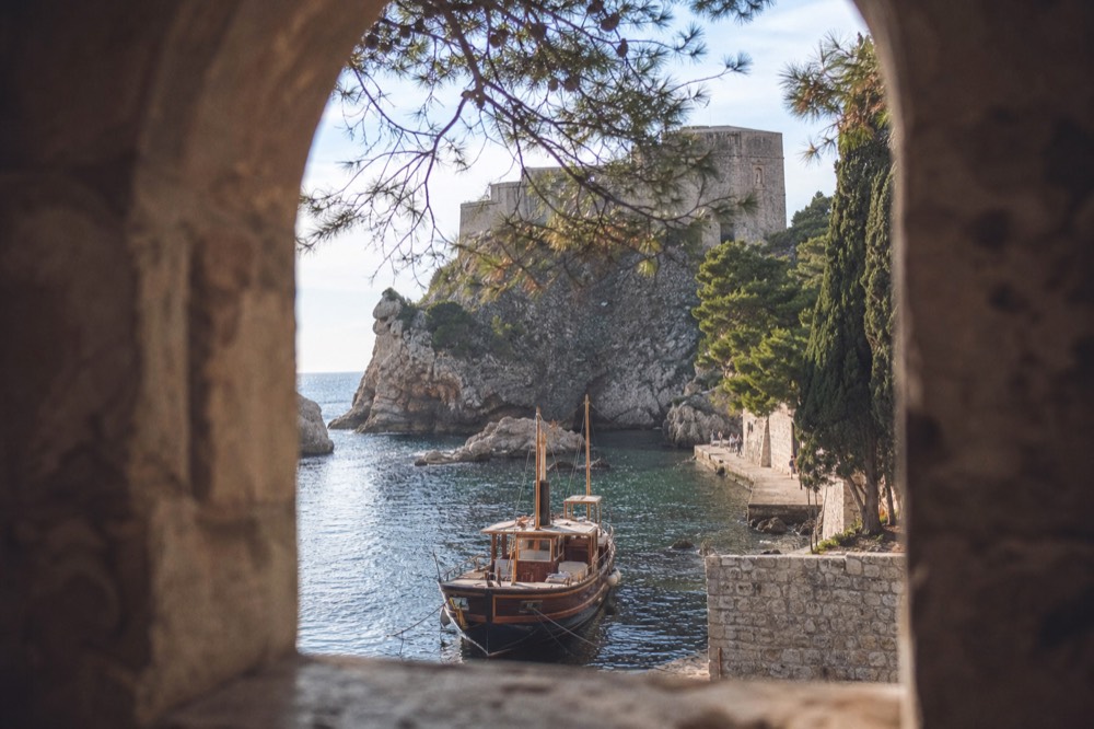Wooden boat moored in the old harbour with stone fortifications rising behind it