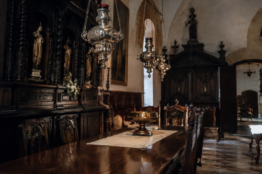 An ornate interior with dark wood furnishings and hanging metal lamps