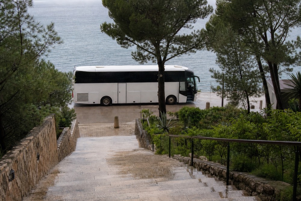 Intercity coach parked at a coastal bus station with the sea behind it