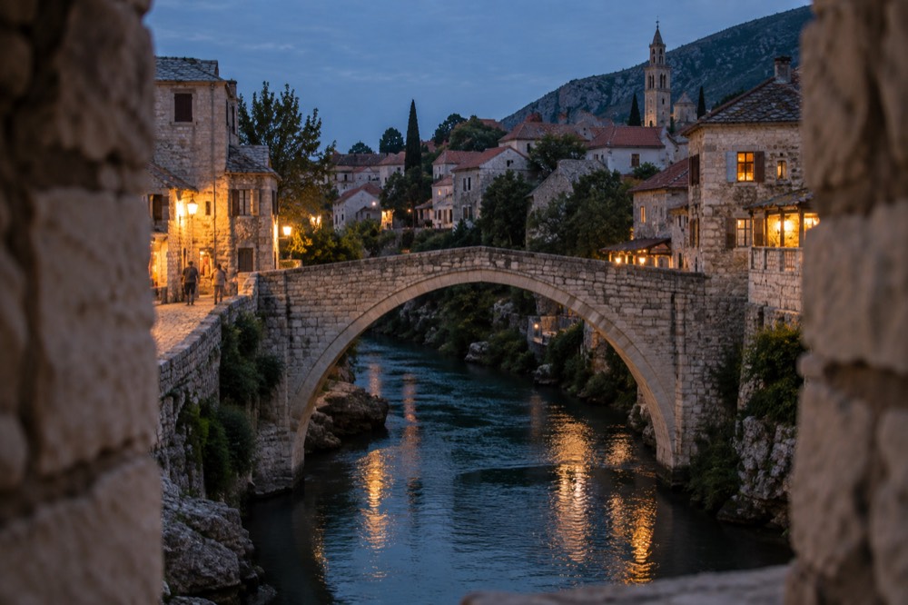 Old stone arch bridge spanning a river with a cobbled town on both banks
