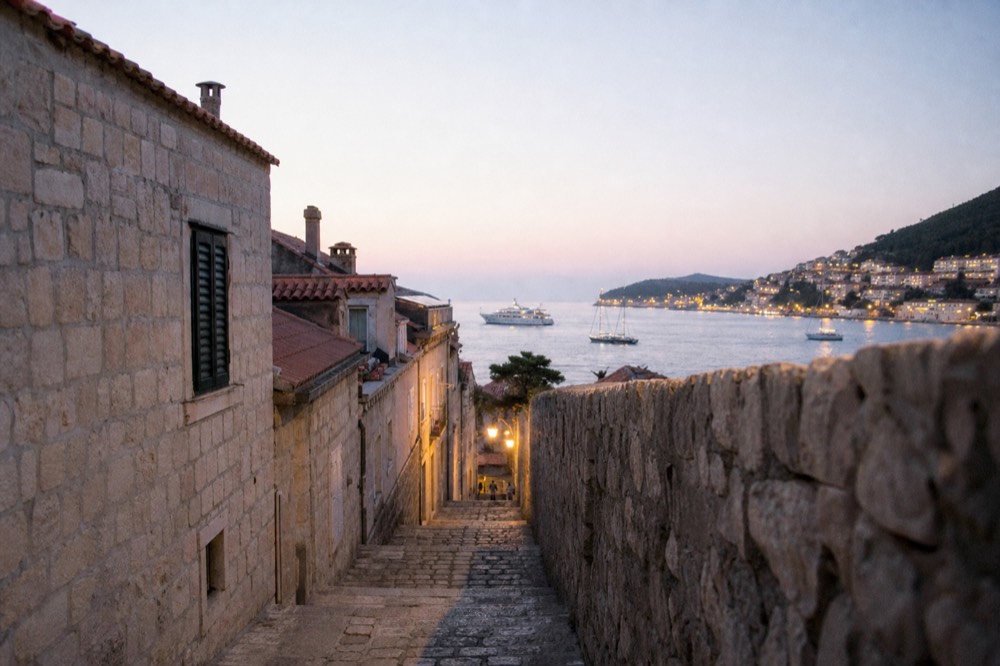 Ferry and sailboats in a harbour at dusk with city lights beginning to show