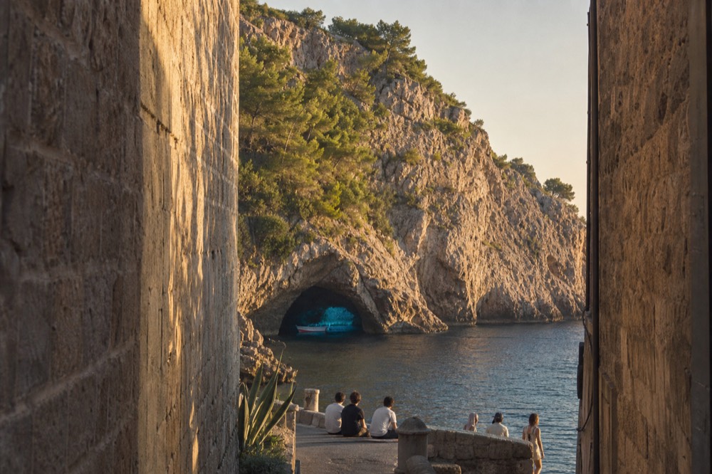 Small boat floating inside a sea cave lit with bright blue water