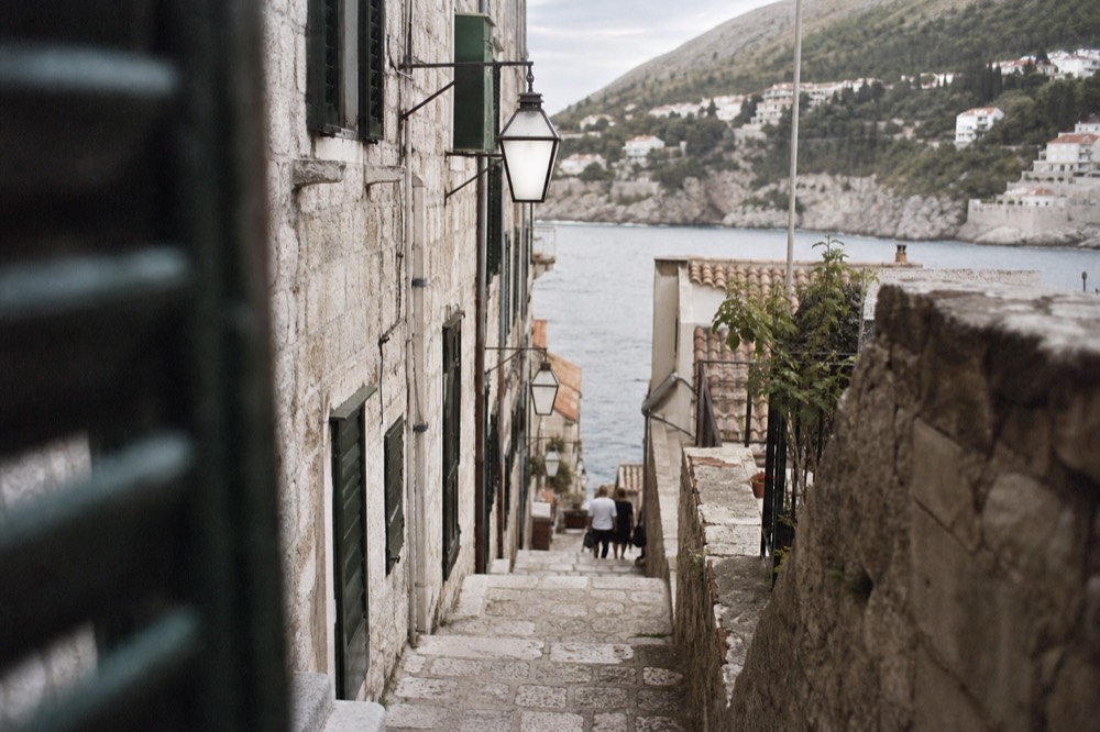 A narrow stone lane in Dubrovnik Old Town with worn limestone steps and shuttered windows