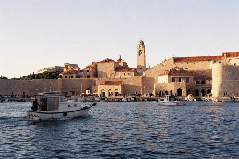 The stone clock tower and historic buildings of Dubrovnik Old Town at dusk with warm light on the facades