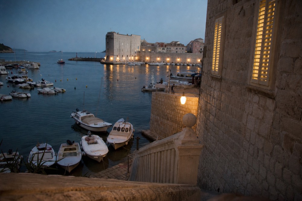 A harbour scene in Dubrovnik with small boats moored beside stone quays and calm water