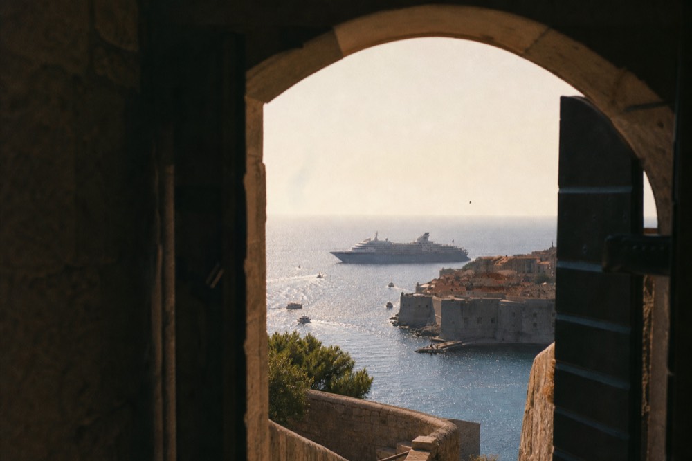 A large cruise ship anchored outside Dubrovnik Old Town with the walled city in the foreground