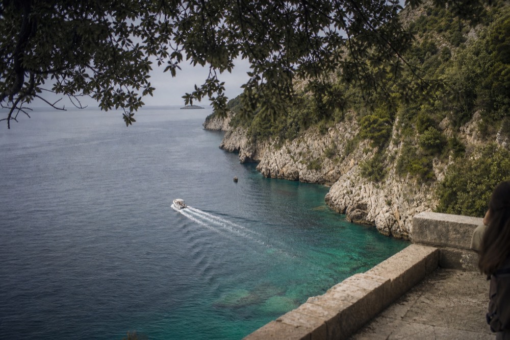 A small boat cruising along limestone cliffs above clear turquoise water