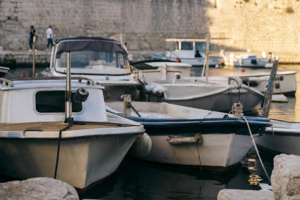 Small boats moored in the old city harbour beneath stone walls