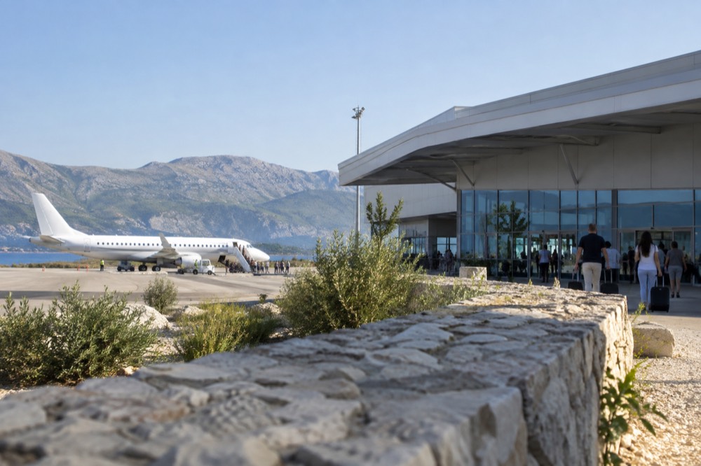 The terminal building of a small coastal airport under a clear morning sky