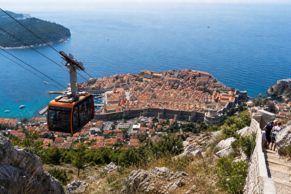 A cable car cabin ascending the slope above Dubrovnik with the Old Town and sea below