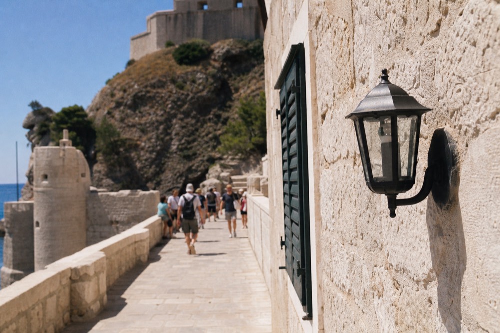 Crowded limestone street lined with stone buildings in bright midday sun
