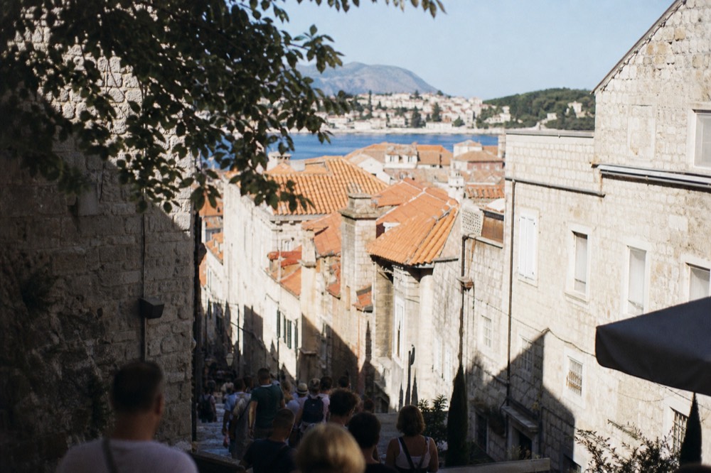 Crowded limestone street in an old town with visitors walking between stone buildings