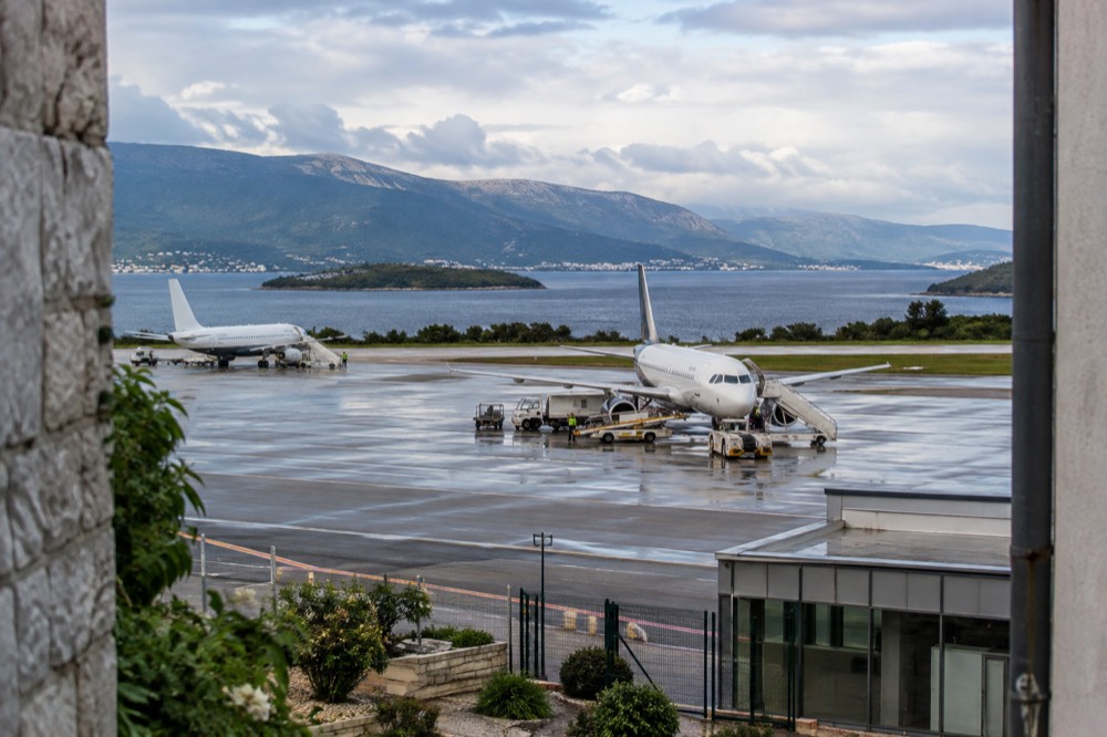 Aircraft on a coastal airport runway with hills and the sea behind