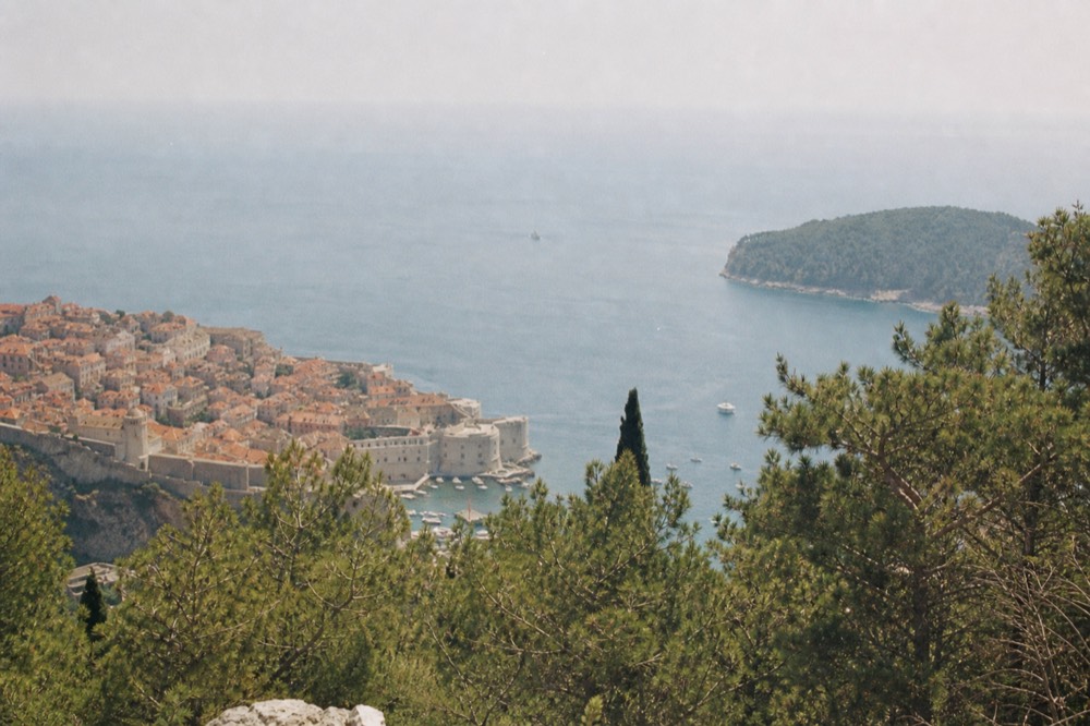 Wide view over Dubrovnik Old Town rooftops toward the Adriatic Sea from a high vantage point
