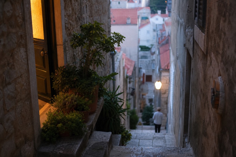 Quiet stone staircase in Dubrovnik Old Town in soft morning light with potted plants beside a doorway