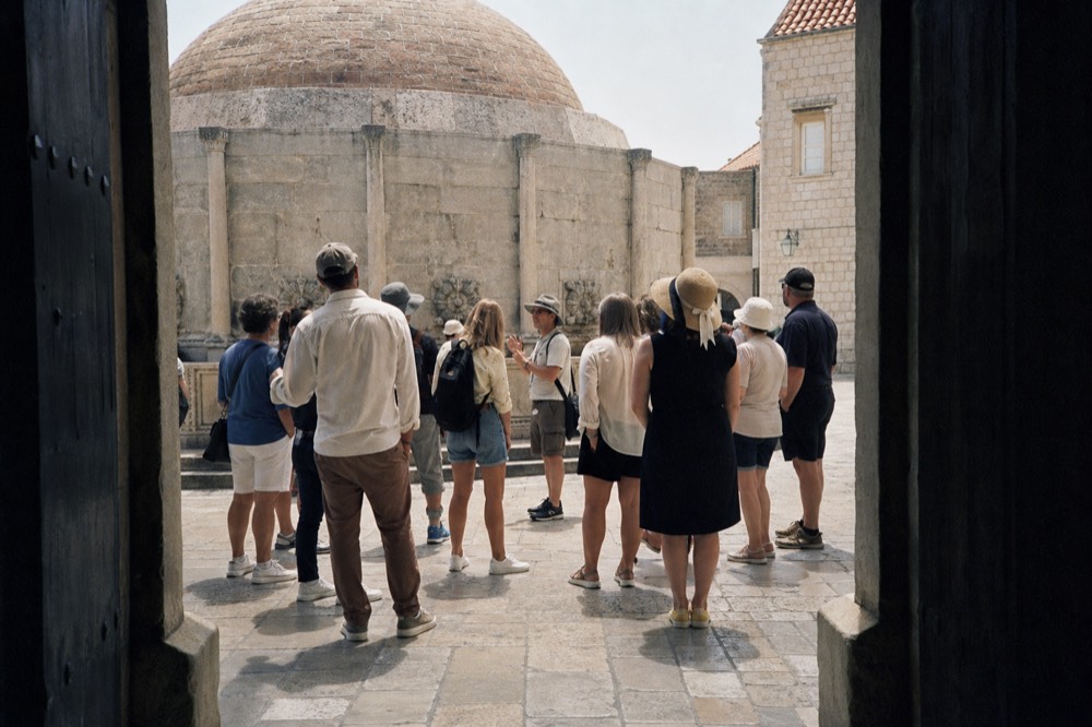 A guide speaking to a small group beside the Onofrio fountain at Pile Gate