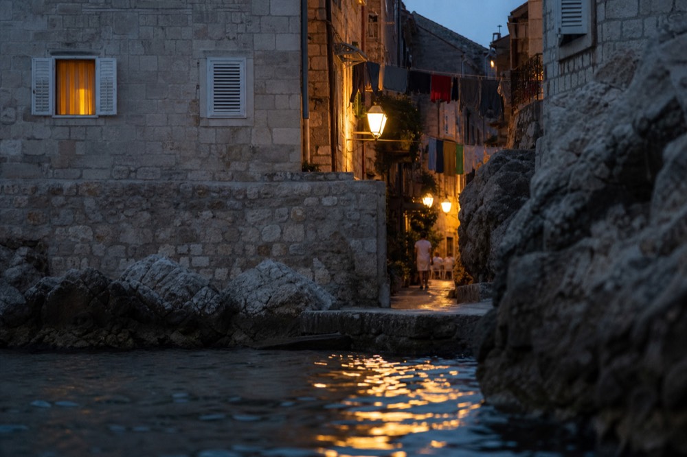A narrow stone lane in the Old Town with laundry strung above and warm lamplight