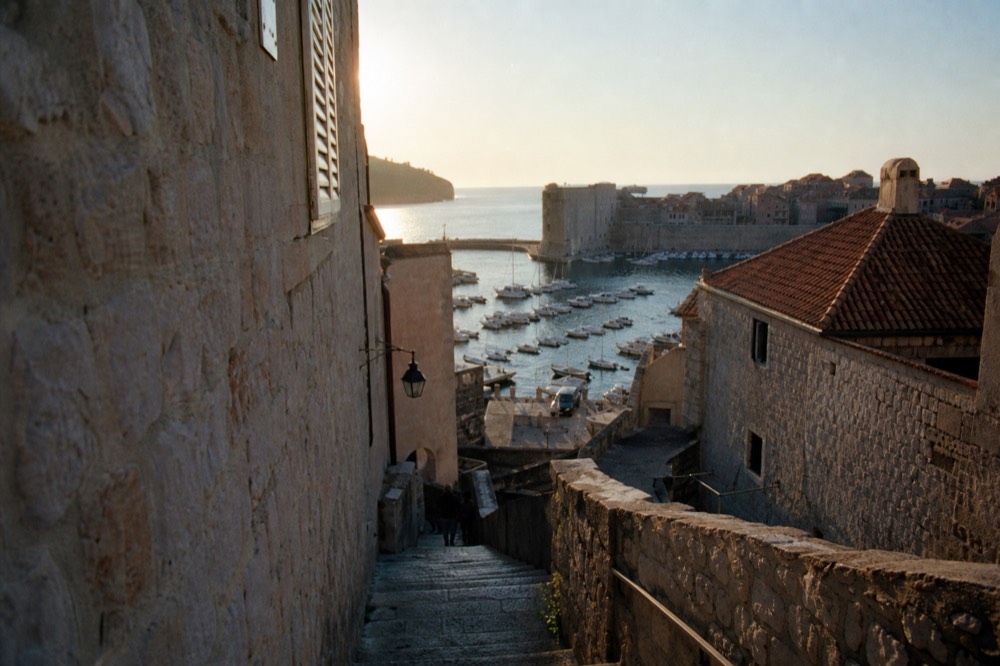 The Old Town harbour at dusk with boats moored and warm light on the walls