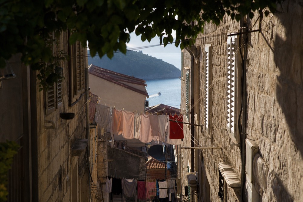 A narrow back lane in the Old Town, laundry lines strung between shuttered stone walls