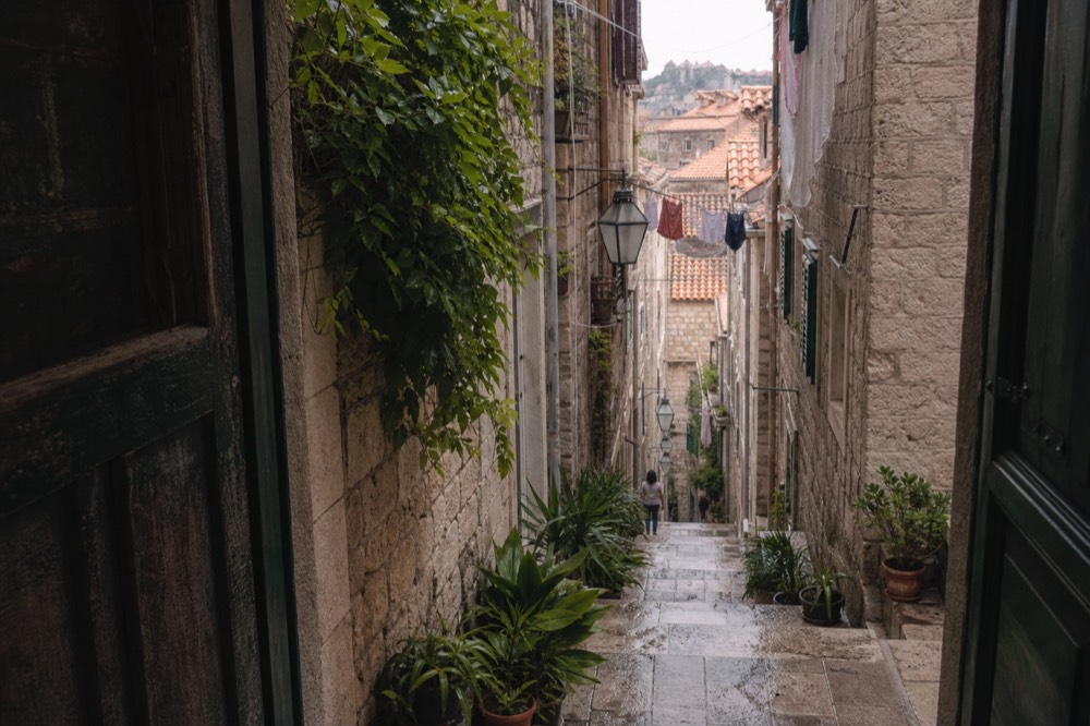 Narrow side street in Dubrovnik with stone steps, laundry lines and potted plants