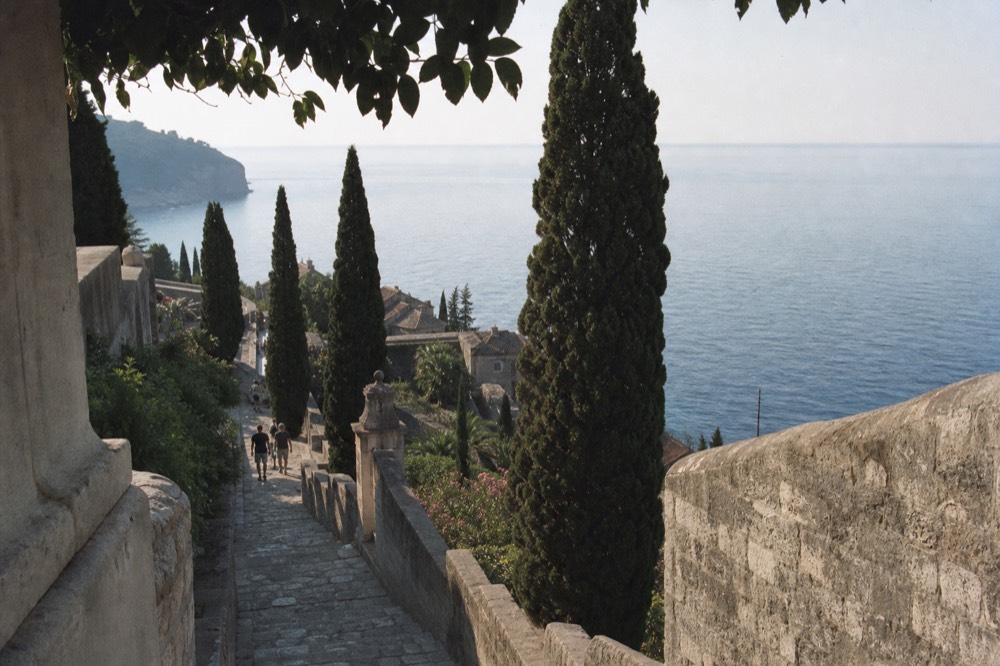 Tall dark cypress trees and stone terraces of a coastal Renaissance garden above the sea