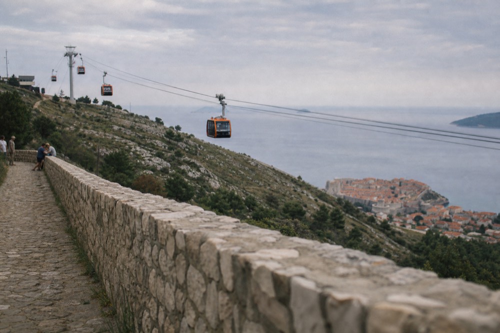 Cable car cabins ascending the hillside above the walled city