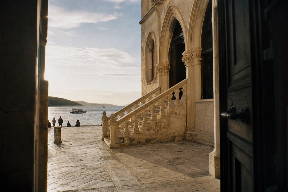 Gothic renaissance palace facade with arched windows and a stone staircase