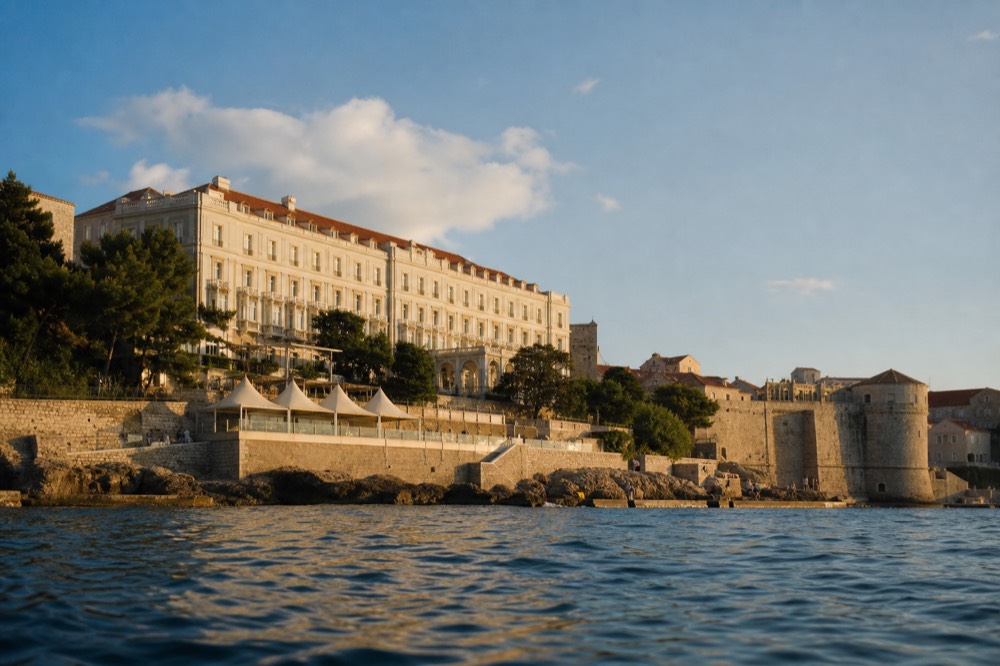 The exterior of the Hilton Imperial Dubrovnik, a cream-coloured historic building with a red-tiled roof, set against the backdrop of the Old Town walls.