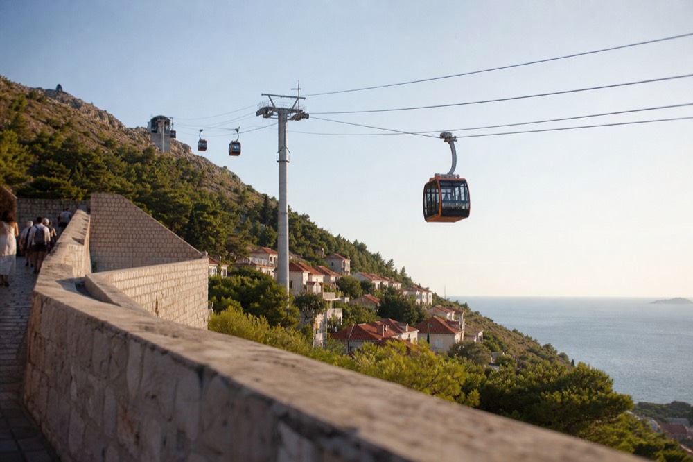 Cable car cabins travelling up the steep slope toward the hilltop station above Dubrovnik