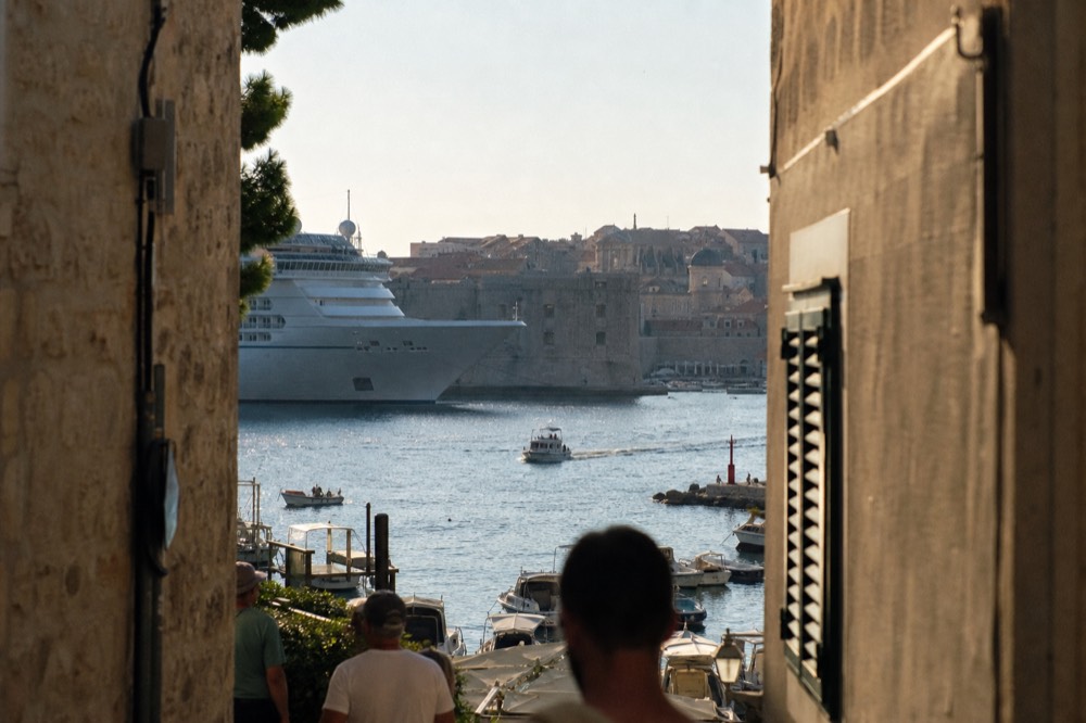 Large cruise ship anchored outside the old harbour with the city walls behind