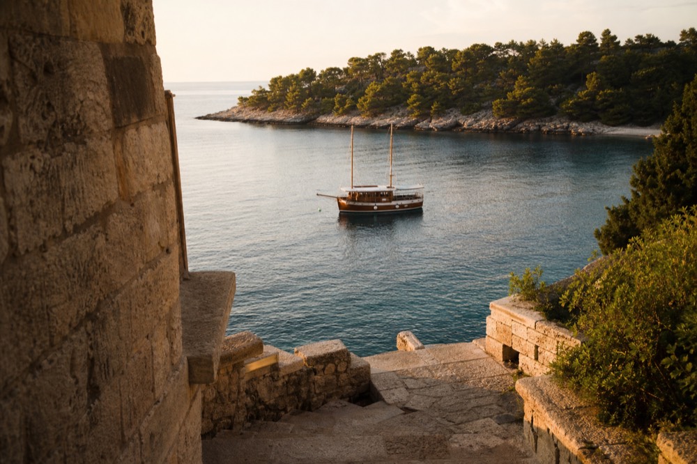 A wooden boat anchored in a small island bay with pine trees along the shoreline