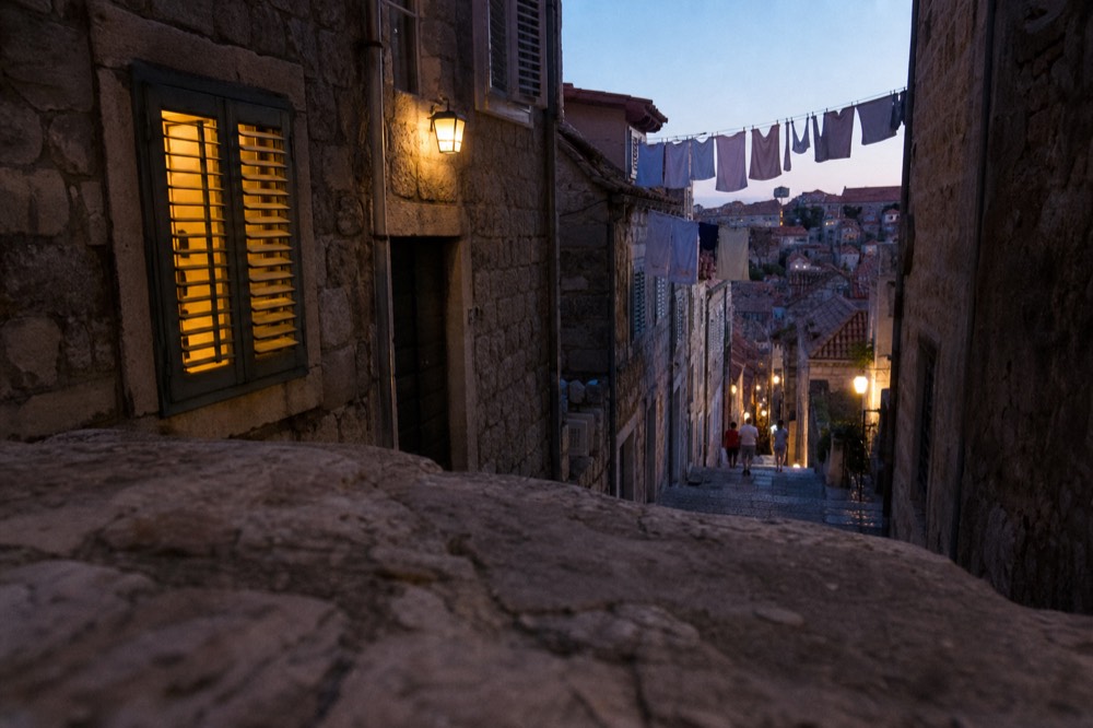 A quiet side street in Dubrovnik Old Town with stone staircases and laundry overhead