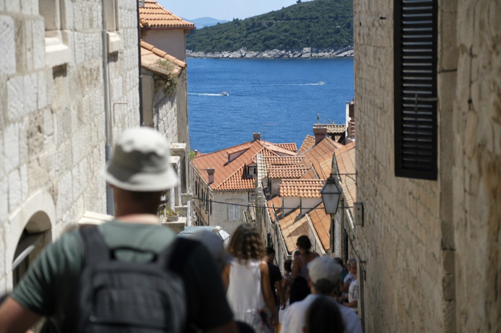 A narrow stone street in Dubrovnik filled with visitors in bright daylight
