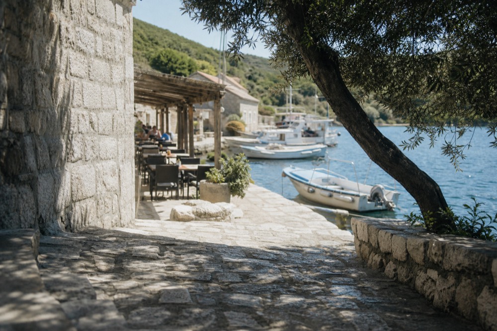 A restaurant terrace by the water on a small Dalmatian island with boats moored nearby