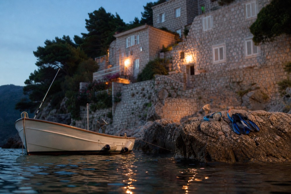 A small boat anchored in a quiet cove with snorkelling gear laid out on a rock