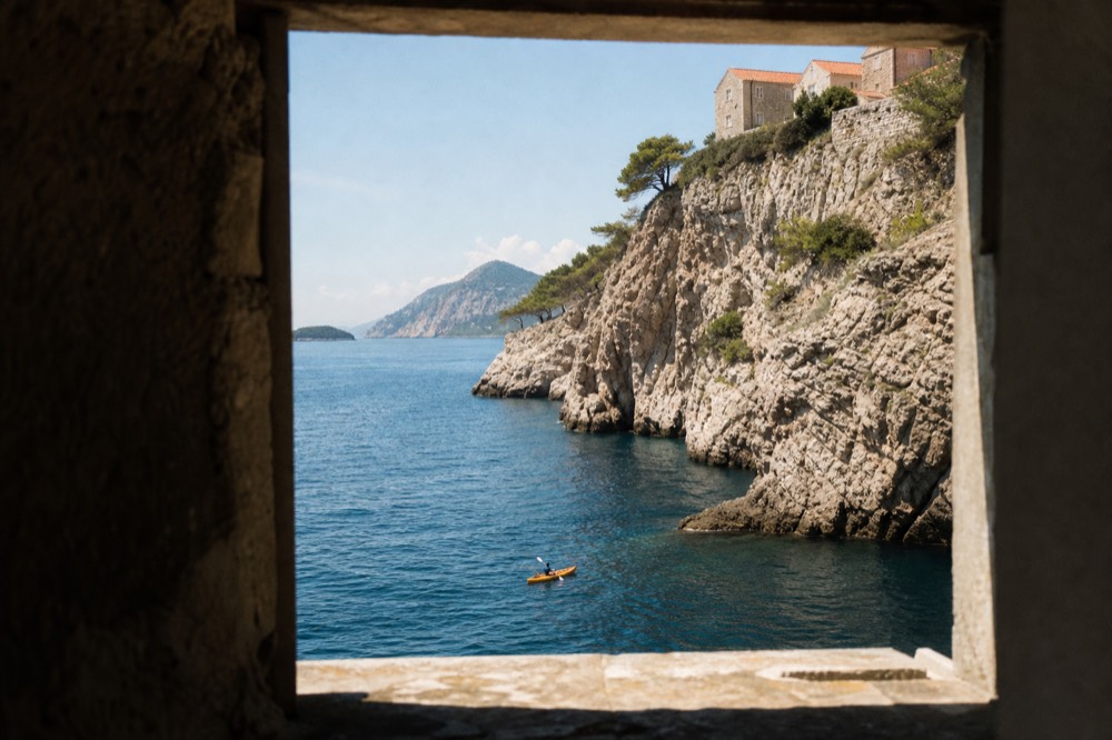 Single kayak paddling close to the limestone cliffs south of Dubrovnik old town