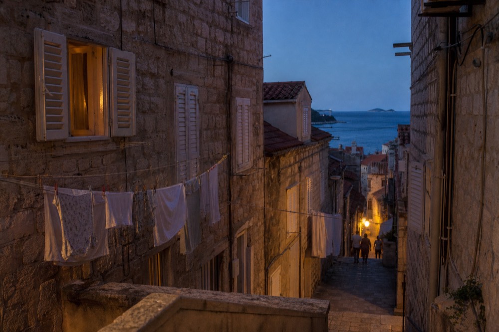 Narrow stone alley with laundry lines and closed shutters in Dubrovnik